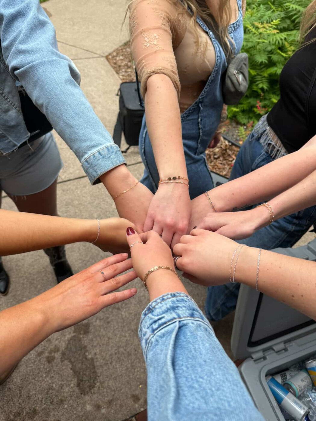 Seven arms extended in a circle, each wearing a permanent bracelet